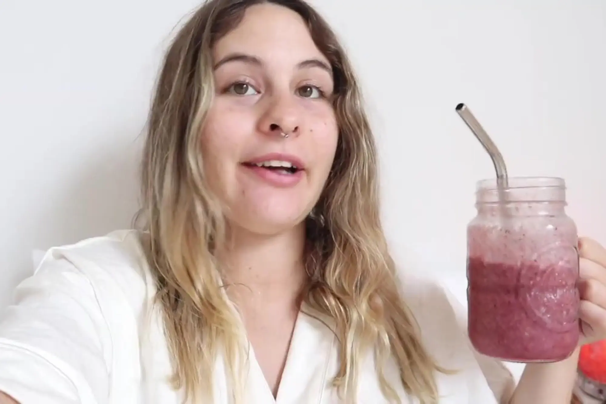 Woman holding smoothie in mason jar with metal straw